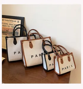 Detalle de bolsos tote de lona en dos tamaños con estampado de París y asas de cuero