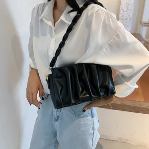 Minimalist black pleated shoulder bag with woven strap and golden metal hardware