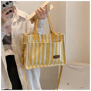 Detail of a striped canvas tote bag featuring large front pockets and dual straps