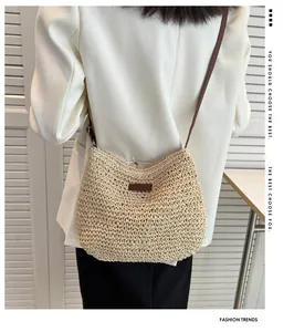 Detailed close-up of woven straw bag with dark brown leather patch and shoulder strap