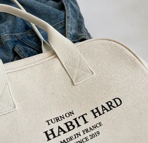 Detail van de versterkte kruisstiksels op de handvatten van de canvas tote bag