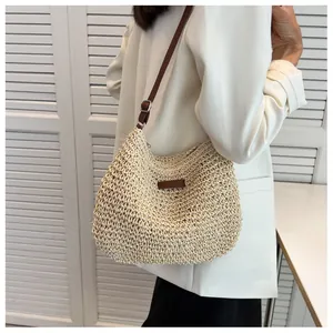 Detail of hand-woven straw shoulder bag with dark brown leather strap and fine grid texture