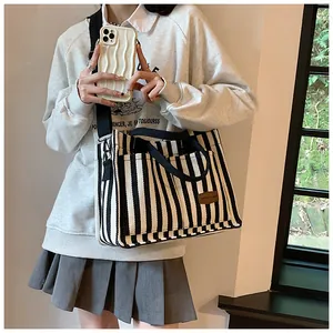 Detail of striped canvas tote bag with brown leather patch and black shoulder straps