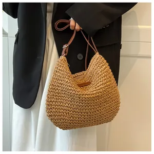 Detail of hand-woven straw shoulder bag with adjustable brown leather strap and tag