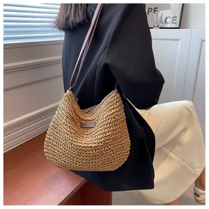 Detail of handwoven straw tote bag with brown leather strap and decorative front patch