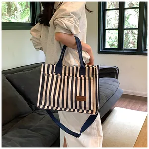 Detail view of the striped canvas tote bag with leather tag and detachable shoulder strap