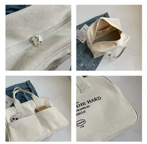 Close-up of canvas tote bag showing dual zippers, inner pocket and Die Hard text
