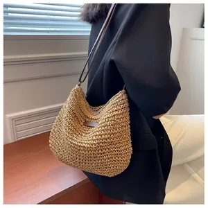 Detail of handwoven straw shoulder bag featuring slim leather straps and a khaki finish
