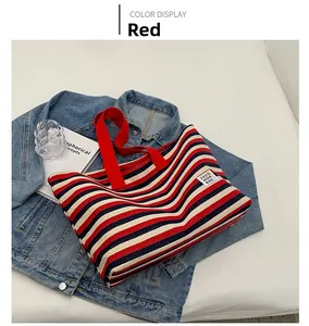 Detail view of large canvas tote bag with red, blue, and white stripes on denim jacket