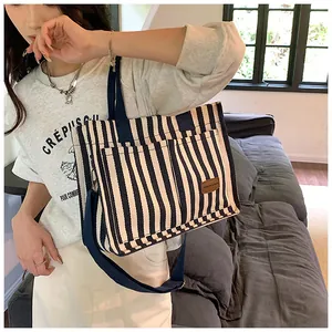 Detail of navy stripe canvas tote bag showing fashion tag, outer pockets and shoulder strap