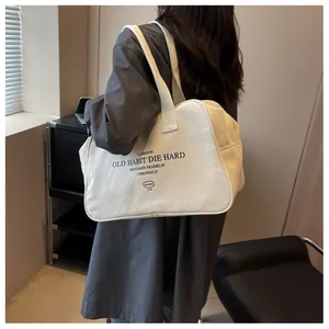 Close-up of a large beige canvas tote bag with black vintage script on wide shoulder strap