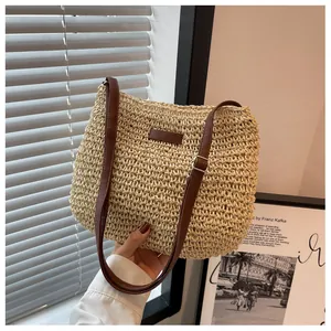 Detail of hand-woven straw shoulder bag featuring adjustable dark brown leather straps