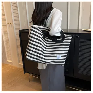 Detail of striped canvas tote bag showing the fashion logo and durable woven handle