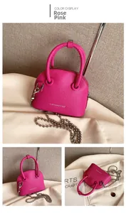Detail view of rose pink lychee leather handbag with silver bead chain and metal zipper