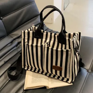 Chic black and white striped canvas tote bag with front pockets and long shoulder strap