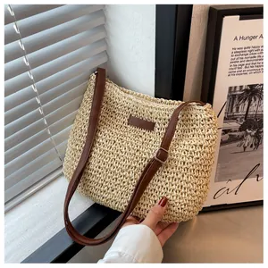 Detailed view of woven straw tote bag featuring brown faux leather strap and patch