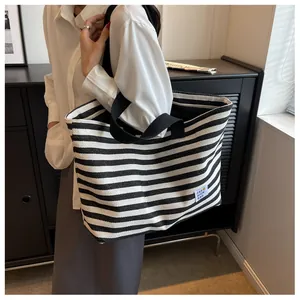 Detail view of large canvas tote bag featuring classic black and white stripes and logo