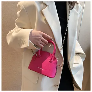 Close-up of fuchsia lychee leather mini bag with silver bead chain and fashion logo
