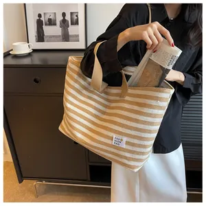 Detail of striped canvas tote bag showing the fashion label and khaki shoulder strap