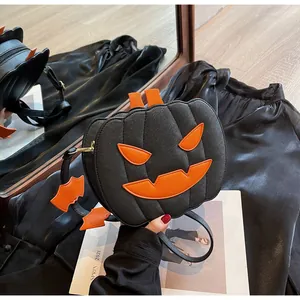 Detail of a black pumpkin crossbody bag with orange bat charm and textured faux leather