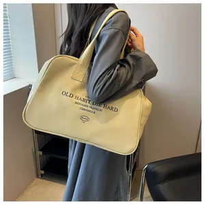 Detail of large canvas tote bag with black typography shown on shoulder of a model