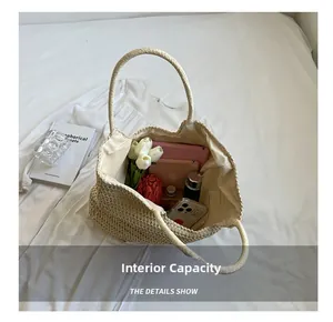 Capacité interne d'un grand sac en paille contenant tablette, parapluie et accessoires