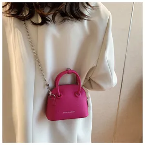 Magenta lychee grain mini crossbody bag with silver bead chain shown on white blazer