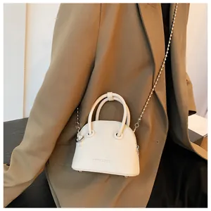 Detail view of mini cream shell crossbody bag with silver bead chain and metal rivets