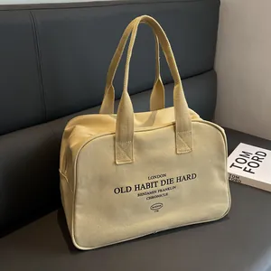Large beige canvas tote bag with black London lettering on a black leather sofa