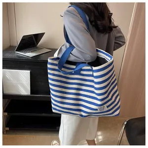 Detail of blue and white striped canvas tote bag with wide shoulder strap and label