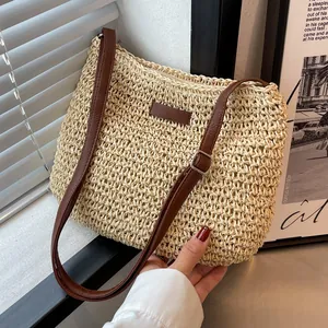 Minimalist beige woven straw shoulder bag with adjustable brown leather strap and zip closure