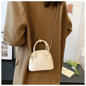 Mini cream crossbody bag with silver bead chain and lychee pattern shown on a model