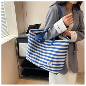 Detail of blue and white striped canvas tote bag with a fashion smile logo label