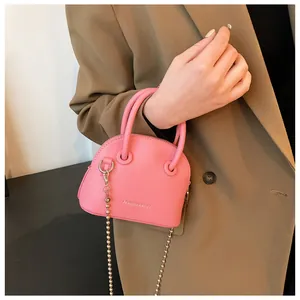 Detail of pink mini pebbled leather dome bag with bead chain and FASHION & BAGS logo