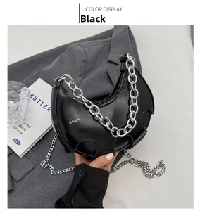 Dettaglio borsa a mezzaluna nera con catena argentata e texture in pelle lucida