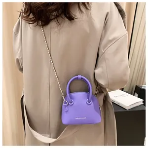 Detail of lavender litchi texture handbag featuring a silver bead chain strap and handle