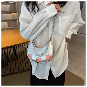 Dettaglio borsa a mezzaluna argento metallizzato con catena spessa su modella donna