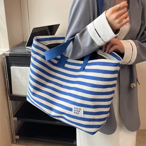 Blue and white striped canvas tote bag with fashion label shown on female model