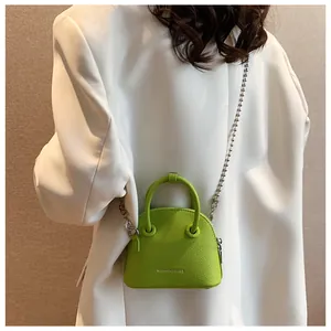 Detail view of lime green crossbody shell bag with silver chain on white blazer