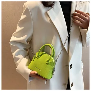 Mini lime green grain leather crossbody bag with silver bead chain shown on a white suit