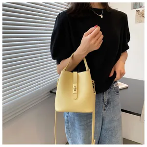Detail of light yellow matte leather bucket bag with gold twist lock and handle