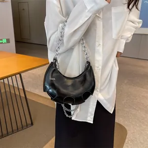 Borsa a mezzaluna in pelle verniciata nera con catena industriale e design traforato