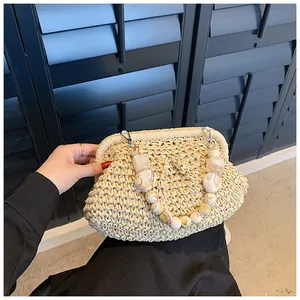 Detail of hand-woven straw bag featuring marble texture bead handle and metal clasp