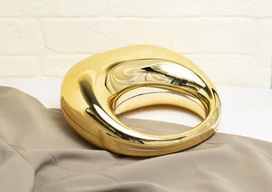Vista macro de bolso de mano acrílico dorado brillante con diseño de mango circular