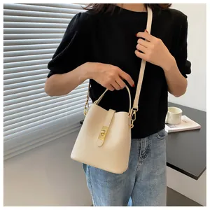 Detailed view of cream leather bucket bag with gold clasp and adjustable strap on shoulder