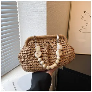 Detail of woven straw handbag with marble-pattern resin bead handle and metal clasp
