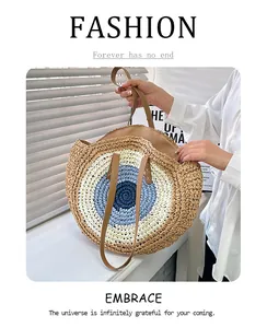 Close-up of hand-woven round straw bag featuring a blue Evil Eye pattern and leather strap