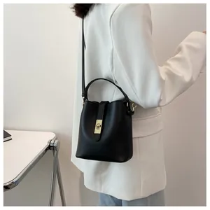 Detail of black matte leather bucket bag featuring gold twist lock and adjustable strap