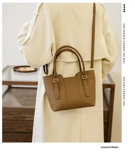 Detailed view of brown litchi pattern leather bag worn by model in a chic indoor setting