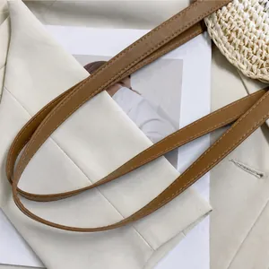 Detail eines braunen Leder-Schultergurts mit Ziernähten an einer Stroh-Tragetasche